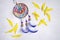 Dreamcatcher with blue feathers between the yellow sunflower petalson an wooden background.