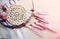 Dreamcatcher with pink feathers and roses on a wooden background.