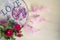 Dreamcatcher with pink feathers and roses on a wooden background.