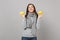 Dreamful young woman in gray sweater, scarf looking up, holding lemons isolated on grey wall background. Healthy fashion