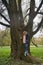 Dreamily schoolgirl in park near giant willow tree in early autumn