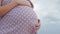 Dreaming pregnant woman in field on background of beautiful clouds