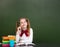 Dreaming teen girl near empty school green chalkboard