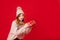 Dreaming winter girl holding christmas present on red background