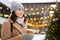 Dreaming woman with hot coffee walking in Christmas market