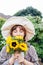 Dreaming young female farmer woman with closed eyes holding and sniffing a sunflowers bouquet on the green garden