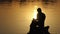 Dreamlike man reads a book on a lake bank at a sunset