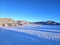 Dreamlike winter wonderland meadow and field with wafts of mist with mountain background under cloudless deep blue sky in morning