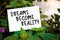 Dreams become reality motivational message written on paper on green garden and plants background. Chasing dreams, success and