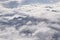 Dreamy aerial view of snowcapped alpine mountain range peaking through heavy clouds