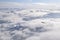 Dreamy aerial view of snowcapped alpine mountain range peaking through heavy clouds