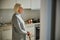 Dreamy aged woman standing in the kitchen