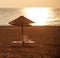 Dreamy beach with sun loungers under parasol on setting sun
