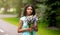 Dreamy black girl in romantic dress with bouquet of flowers at park