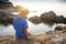 Dreamy child on sea. Little boy sits on rocky beach at sunset and look at surface of waves sea water