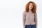 Dreamy, creative good-looking redhead curly girl in blouse, jeans, looking up thoughtful, smiling devious, picturing