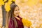 Dreamy cute little girl in autumn clothes in a park with yellow leaves. A smiling child is playing in the park