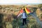 Dreamy cute little kid with colorful kite behind his back standing in field on sea horizon background