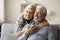 Dreamy elderly aged couple in love hugging at home, laughing