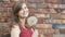 Dreamy girl with fluffy big dandelion on the background of the red brick wall, beautiful young woman smilng and flirting, female e