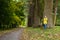 Dreamy girl is leaning on trunk of large old tree in park