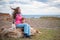 Dreamy girl sitting with two little dogs on cold sea shore with copy space