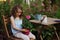 dreamy happy child girl relaxing in summer evening garden with heranium flower in pot