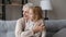 Dreamy little girl sit on knees of loving elderly grandmother