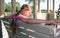 Dreamy looking girl sitting on swing bench in the park