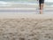 Dreamy low section of barefoot man walking into the waves on a sandy beach