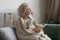 Dreamy middle aged woman wrapped warm blanket relaxing at home