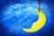 Dreamy moon hanging on string with night sky background.