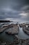 Dreamy seascape for background. Beach with rocks and stones. Low tide. Blurred foggy water. Cloudy sky. Slow shutter speed. Soft