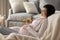 Dreamy smiling pregnant woman touching belly, relaxing in cozy chair