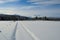 Dreamy snowy field in winter sunshine with mountain and forest