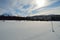 Dreamy snowy field in winter sunshine with mountain and forest