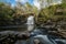 Dreamy waterfall and river in sunny woodlands