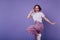 Dreamy white girl in stylish sneakers jumping on purple background in studio. Debonair short-haired