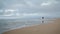 Dreamy woman walking ocean beach on cloudy day. Romantic african american girl