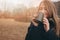 Dreamy young woman drinking hot tea outdoor on the walk, enjoying traveling in autumn