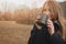 Dreamy young woman drinking hot tea outdoor on the walk, enjoying traveling in autumn