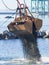 Dredge Clamshell Bucket unloading gravel in the water of a port