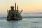 Dredging vessel operating at sunset.