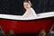 Drenched girl in a blouse sitting in the bathtub