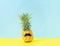 Dressed cheerful pineapple with mustache a blue yellow background. Creative concept of summer vacation . Glitch effect.