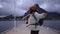 Dressed in a wool sweater and hat, a young traveler girl carrying a backpack walks towards the pier on the Lofoten