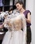 Dressmaker fixing white lace wedding dress on a mannequin in tailor studio