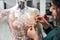 Dressmaker fixing white lace wedding dress on a mannequin in tailor studio