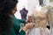 Dressmaker fixing white lace wedding dress on a mannequin in tailor studio