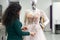 Dressmaker fixing white lace wedding dress on a mannequin in tailor studio